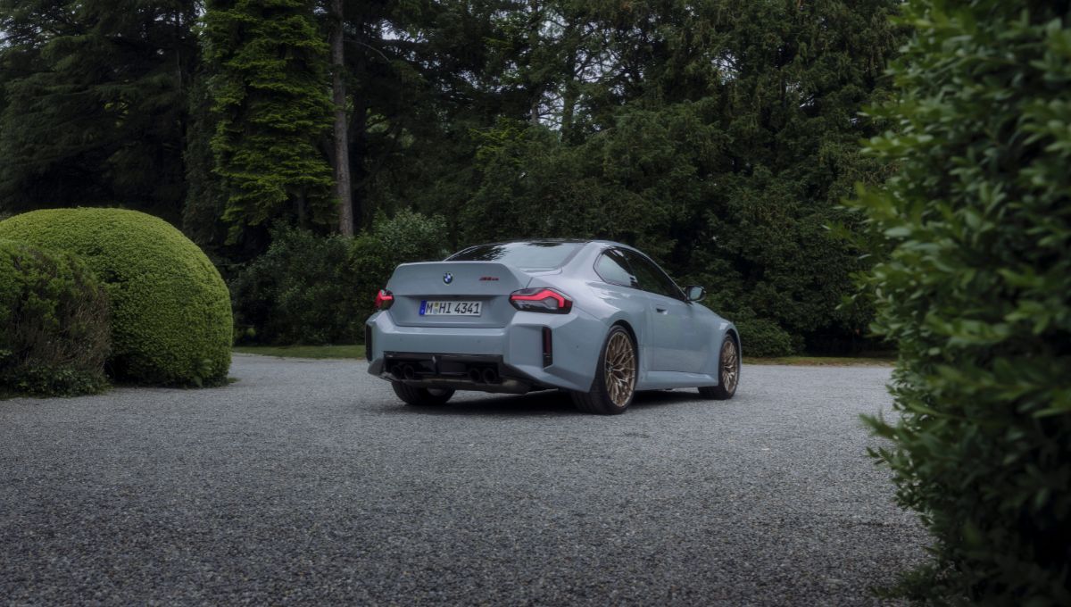 foto que mostra parte da lateral direita e da traseira do BMW M2 CS em meio a um cenário recheado de arvores e plantas
